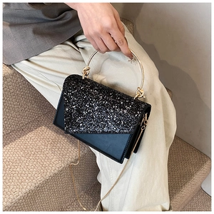 Detail of elegant black sequin handbag with round gold metal handle and chain strap