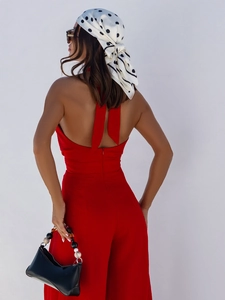 Detail shot of a backless halter neck red jumpsuit with a polka dot scarf accessory