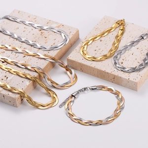 Set of gold, silver, and tricolor hand-woven stainless steel snake chains on beige stone