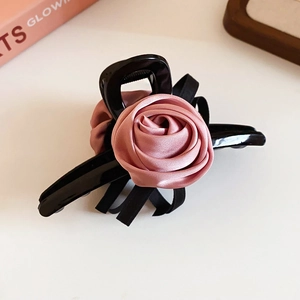 Detail of elegant black hair claw clip featuring a large pink satin silk rose ornament