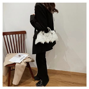 White PU bat-shaped crossbody bag with spider web embroidery detail on a model