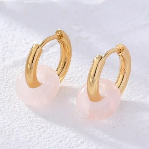 Macro view of gold-plated hoop earrings featuring pink translucent stone rings