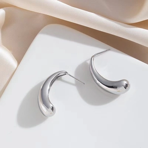 Polished silver teardrop earrings on elegant silk background in a minimalist aesthetic