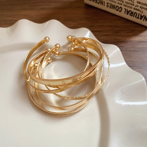 Detail of gold layered open bangles set featuring LOVE engraving and small bead accents