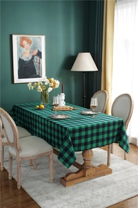 Close-up detail of green and black buffalo plaid tablecloth on a wooden dining table