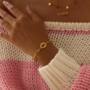 Gros plan d'un bracelet gourmette en plaqué or 18 carats sur un pull en maille rose