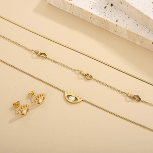 Detail of gold evil eye jewelry set with heart charms and snake chain necklace
