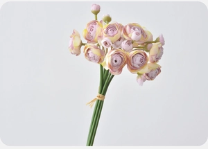 Detailed view of artificial lilac and yellow ranunculus bouquet tied with rustic straw rope