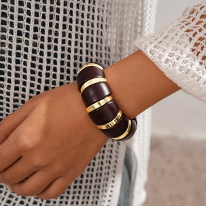 Gros plan d'un bracelet extensible rétro en acrylique avec anneaux métalliques dorés