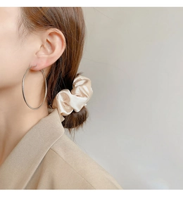 Close-up of minimalist large silver hoop earrings worn with elegant outfit and soft lighting