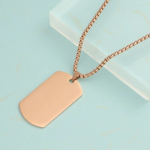 Polished rose gold stainless steel rectangle dog tag necklace on a blue marble background