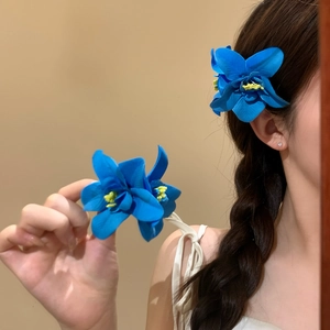 Fermaglio per capelli con fiore blu vibrante su modella per acconciature da mare