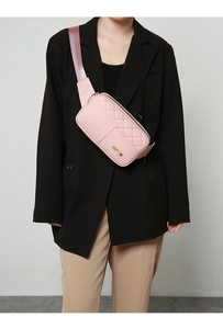 Pink quilted crossbody waist bag shown as a chest pack on a model in a black blazer