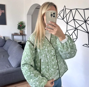 Detail of green paisley quilted jacket showing the vintage print and stitching