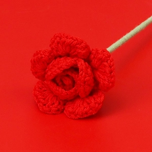 Macro view of handmade red crochet rose with detailed knit texture and green stem