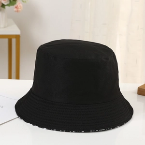 Detail view of a classic black cotton twill bucket hat on a white surface with soft light