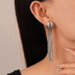 Close-up of geometric metallic tassel earrings with elegant long fringe on a model