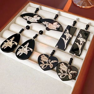 Close-up of geometric black and white floral earrings in various shapes like heart and fan