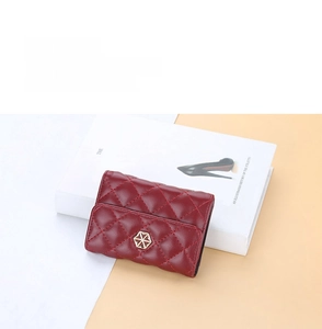 Detail of red quilted card holder featuring a gold hexagonal clasp on a stylish background