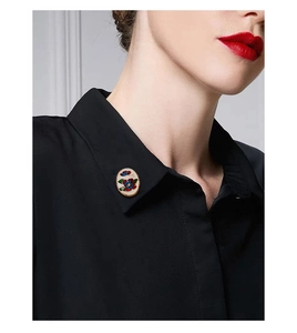 Macro detail of enamel flower butterfly brooch pinned on a black shirt collar