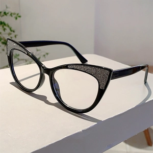 Close-up of black cat-eye glasses frame with silver glitter accents on geometric stand