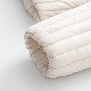 Detail of elastic cuffs and horizontal quilting on a beige padded jacket for women