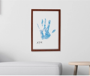 Detailed view of DIY family handprint art in a vintage wooden frame on a modern white wall