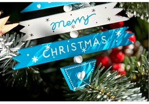 Close-up of blue and white 'Merry Christmas' wooden hanging sign on festive tree branch