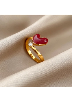Detailed close-up of 18k gold heart ring with red enamel and zircon on silk background