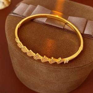 Detail of gold heart bangle with pavé zircons on a luxury brown velvet jewelry box