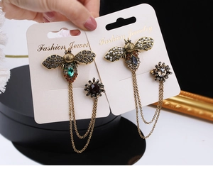 Detail of vintage bee brooches with layered chains and colorful rhinestones