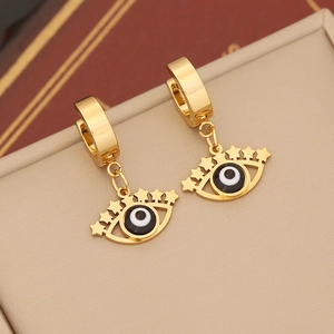Macro shot of gold evil eye earrings with star cutouts on a beige jewelry box