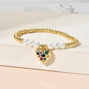 Detail of beaded bracelet with gold metal beads, white pearls and a colorful heart pendant