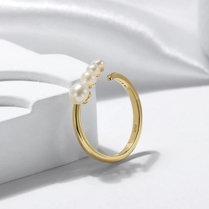 Elegant gold S925 sterling silver open ring with natural pearls on a white podium