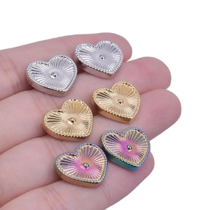 Macro detail of heart-shaped stainless steel earrings in gold, silver, and rainbow finishes