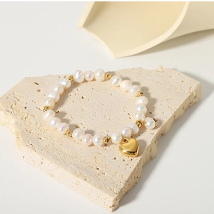 Detail of freshwater pearl bracelet with gold beads and a mirror-polished heart pendant