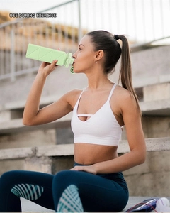 Woman in white sportswear using the light green collapsible silicone water bottle outdoors