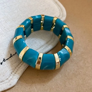 Close-up of chunky acrylic bangle featuring blue marble blocks and gold metal spacers