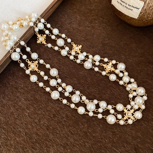 Detailed close-up of layered pearl necklace with diamond-encrusted cross charms and gold spacers