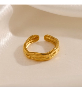 Macro view of gold-plated ring showing irregular lava texture on white silk background