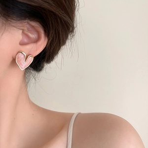 Pink heart-shaped stud earrings with gold edges and marble texture on model