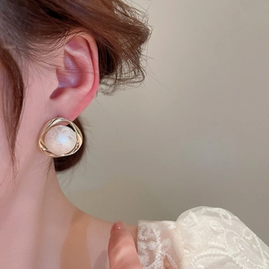 Close-up of elegant gold geometric earring with white pearl worn by a model