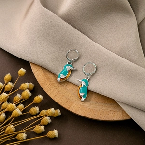 Detail of vintage kingfisher earrings with turquoise enamel on a rustic wood base