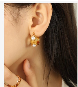 Detail view of 18k gold stainless steel C-shaped earrings with white pearl inlay
