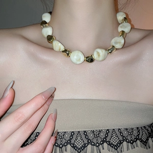 Close-up of vintage acrylic beaded necklace with irregular cream and gold accents
