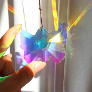 Handheld butterfly crystal prism suncatcher reflecting rainbow light near a window