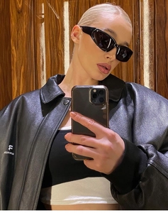 Close-up of black cat-eye sunglasses paired with a stylish oversized faux leather jacket