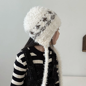 Close-up of plush knit earflap hat for kids featuring soft faux fur and long braided tassels