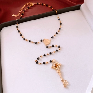 Détail du collier pendentif clé vintage avec perles noires et médaille Saint-Benoît