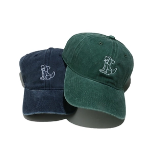 Detail of navy and green washed cotton baseball caps with white dog embroidery